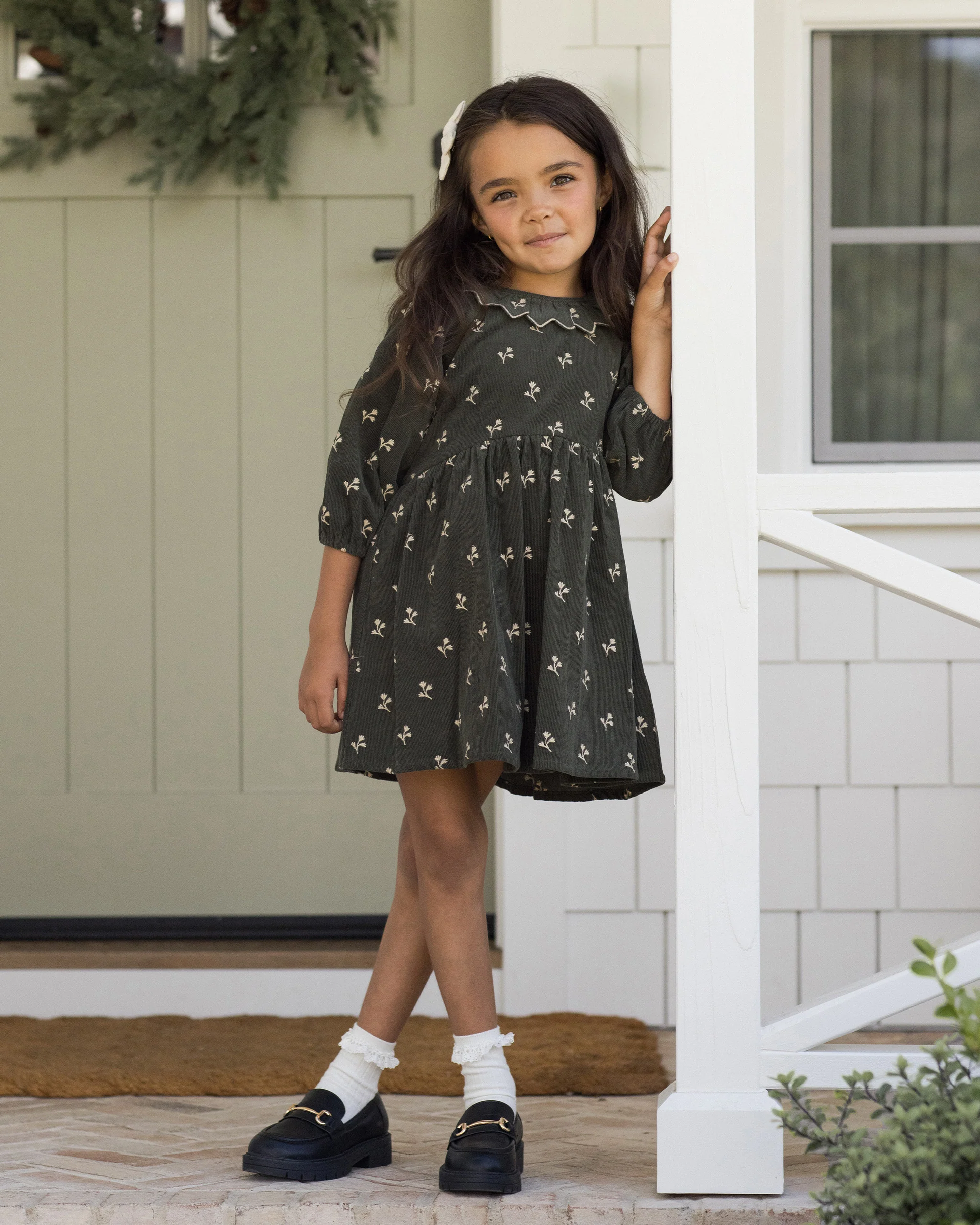 Children’s Freya Dress in fine corduroy featuring a ruffle collar, balloon sleeves, floral embroidery, and zipper back closure.